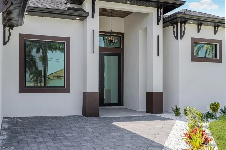 Doorway to property featuring roof with shingles and stucco siding
