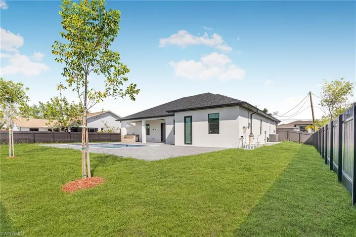 Rear view of property featuring a fenced backyard, a yard, a fenced in pool, stucco siding, and a patio area