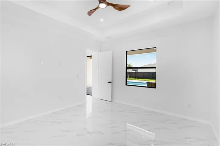 Spare room featuring marble finish floor, a tray ceiling, recessed lighting, and baseboards