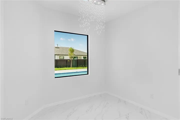 Spare room with a chandelier, marble finish floor, and baseboards