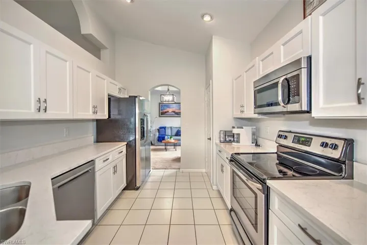 Kitchen with white cabinets, appliances with stainless steel finishes, and light tile patterned floors