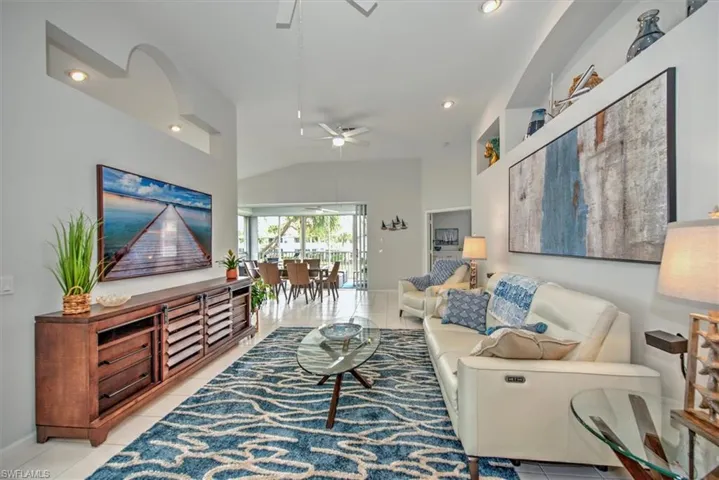 Living room with ceiling fan, light tile patterned floors, and vaulted ceiling