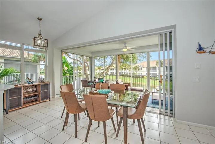 Sunroom with ceiling fan with notable chandelier, a wealth of natural light, and lofted ceiling