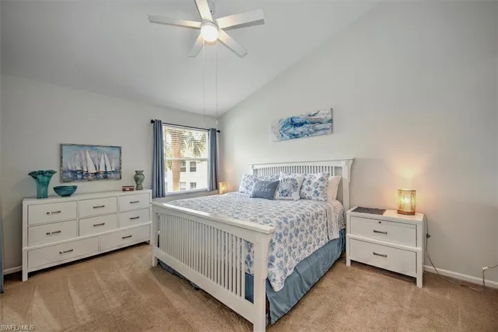 Bedroom featuring ceiling fan, light colored carpet, and lofted ceiling