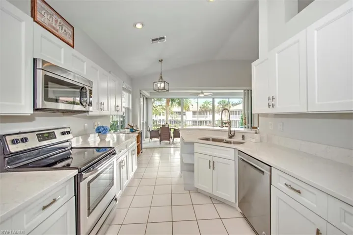 Kitchen featuring white cabinets, stainless steel appliances, sink, vaulted ceiling, and ceiling fan