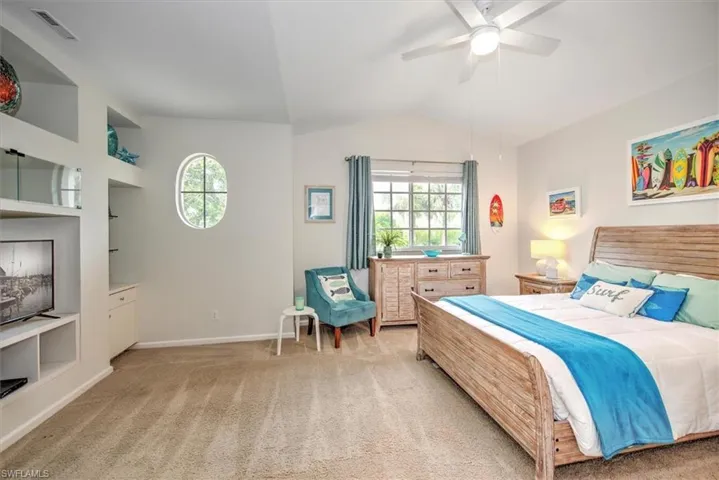 Carpeted bedroom featuring ceiling fan and lofted ceiling