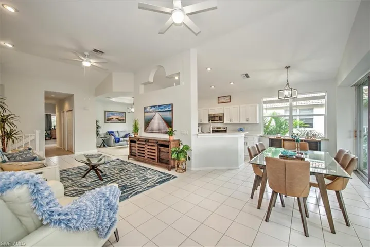 Living room featuring ceiling fan, light tile patterned floors, and lofted ceiling