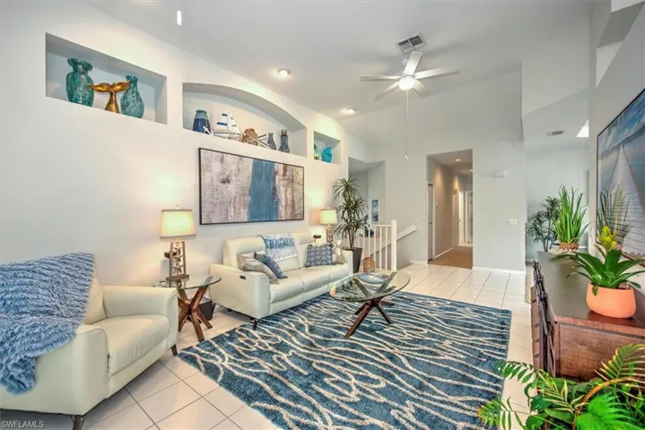 Tiled living room featuring ceiling fan and high vaulted ceiling