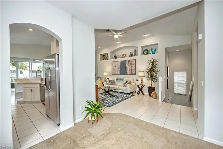 Hallway with sink, vaulted ceiling, and light tile patterned flooring
