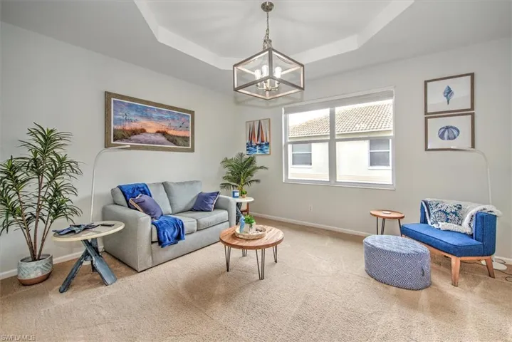 Living room with an inviting chandelier, carpet, and a tray ceiling