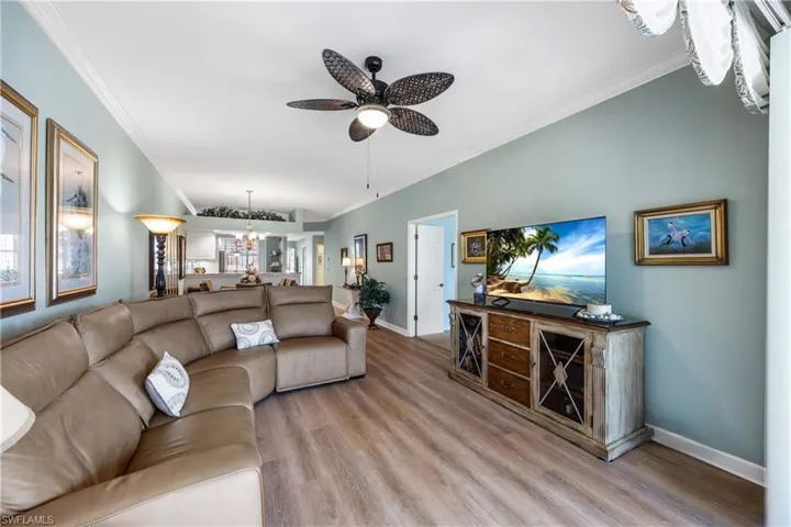 Living room with ornamental molding, a chandelier, light wood-style flooring, and a ceiling fan