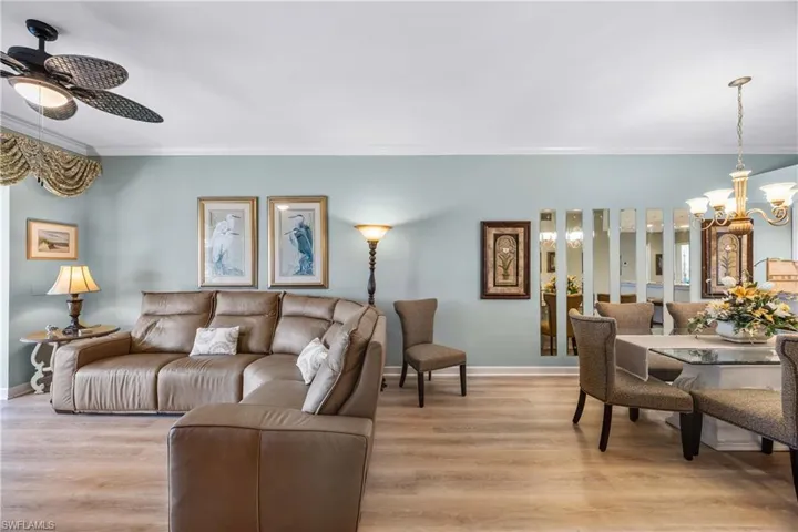 Living room featuring a chandelier, ornamental molding, light wood finished floors, and a ceiling fan
