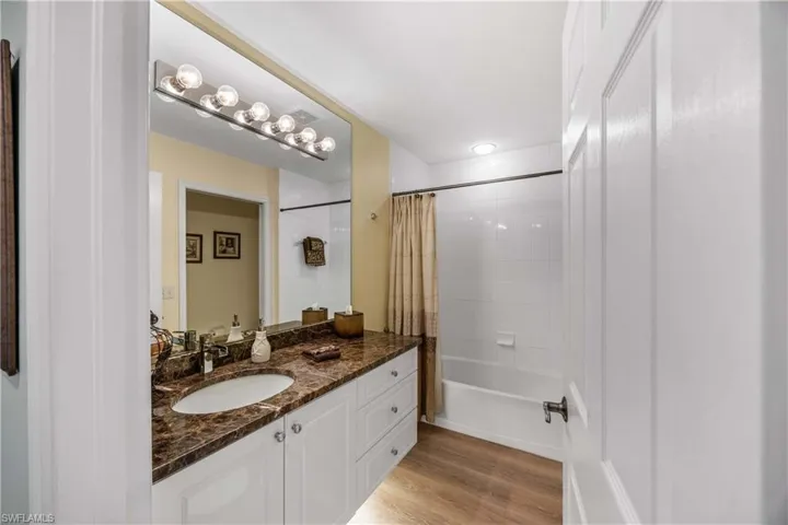Full guest bathroom featuring shower / bathtub combination , vanity, and under cabinet lighting  and new floors
