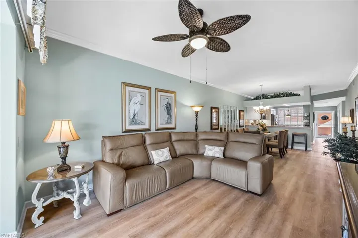 Living room with crown molding, wood finished floors, a chandelier, and a ceiling fan