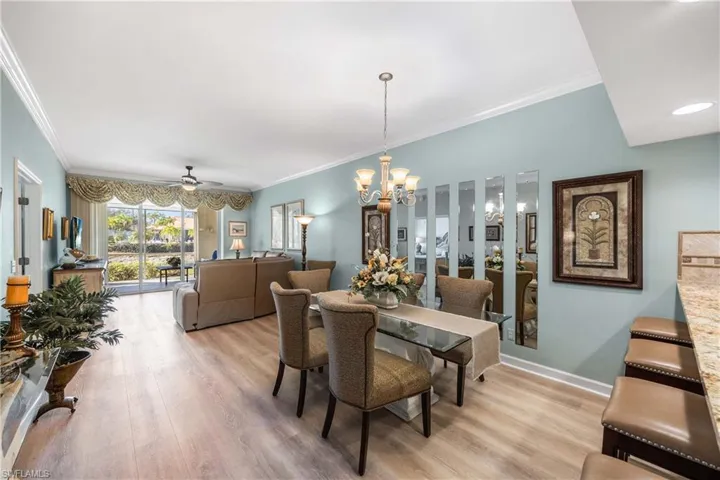 Dining area with crown molding, ceiling fan, light wood-style flooring, and a chandelier