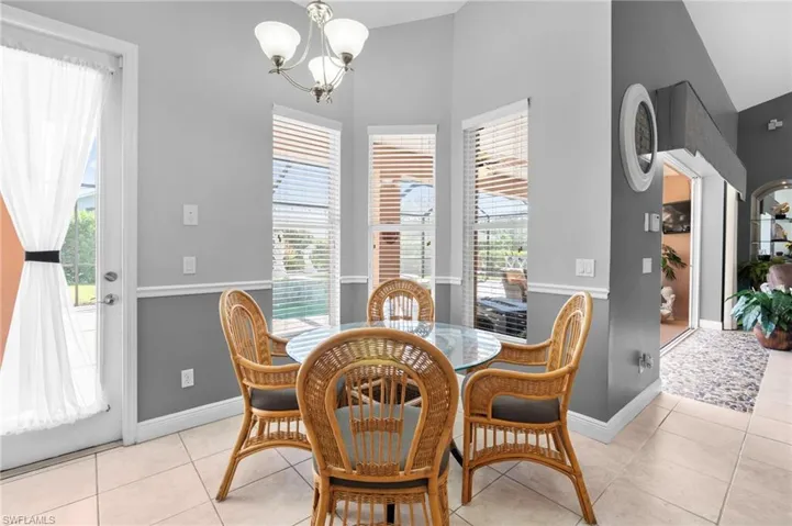 Tiled eat in kitchen area featuring high vaulted ceiling, a notable chandelier, and a wealth of natural light