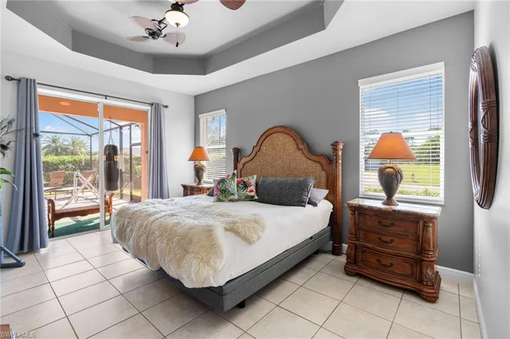 Bedroom with a raised ceiling, access to exterior, ceiling fan, and light tile patterned floors