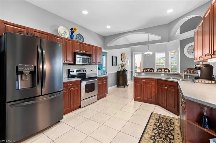 Kitchen featuring stainless steel appliances, sink, pendant lighting, light tile patterned floors, and a chandelier