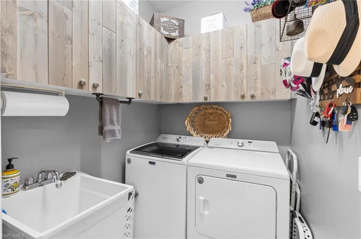 Laundry area featuring washer and clothes dryer, sink, and cabinets