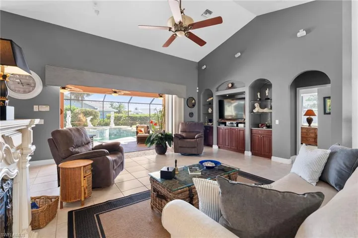 Living room with built in shelves, high vaulted ceiling, ceiling fan, and light tile patterned flooring