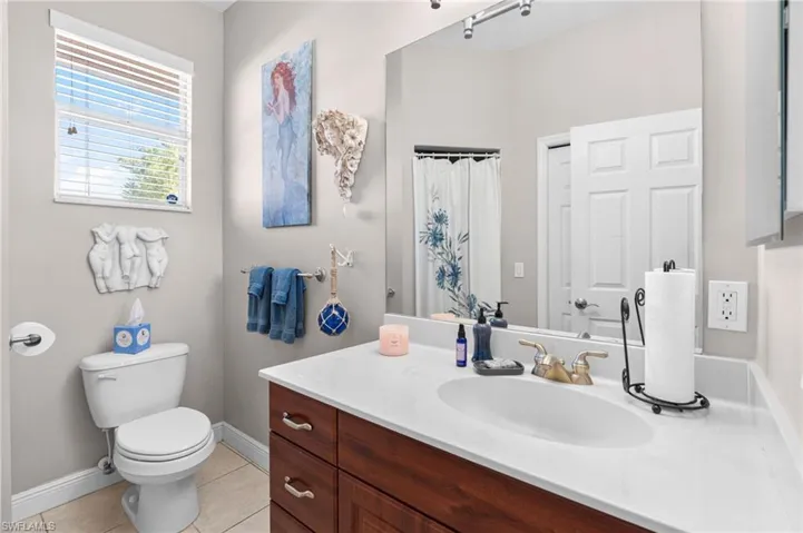Bathroom featuring tile patterned floors, curtained shower, vanity, and toilet