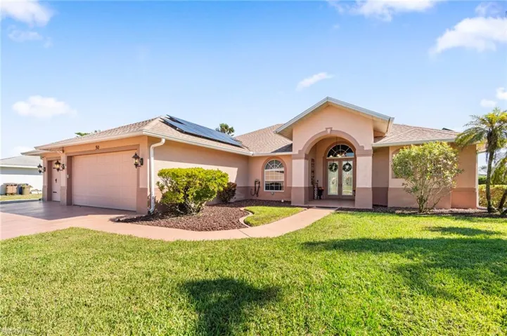 View of front of home featuring solar panels, a garage, and a front yard on .34 acres