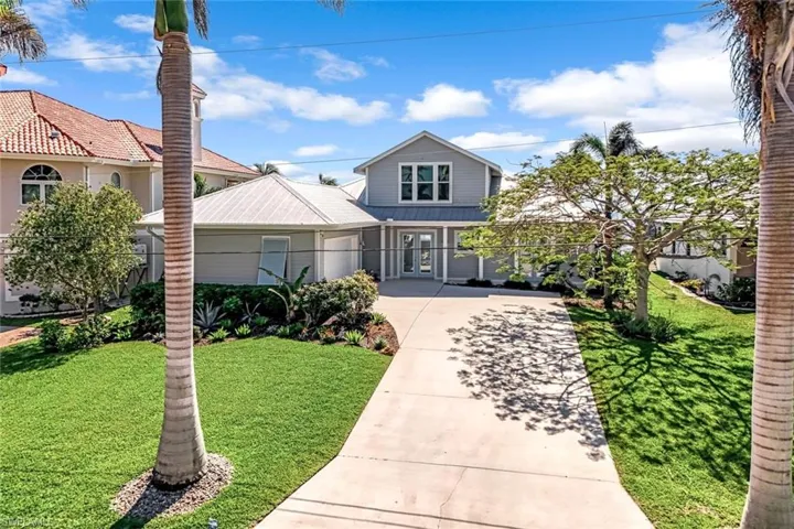 Traditional-style house with a front yard, driveway, and a metal roof