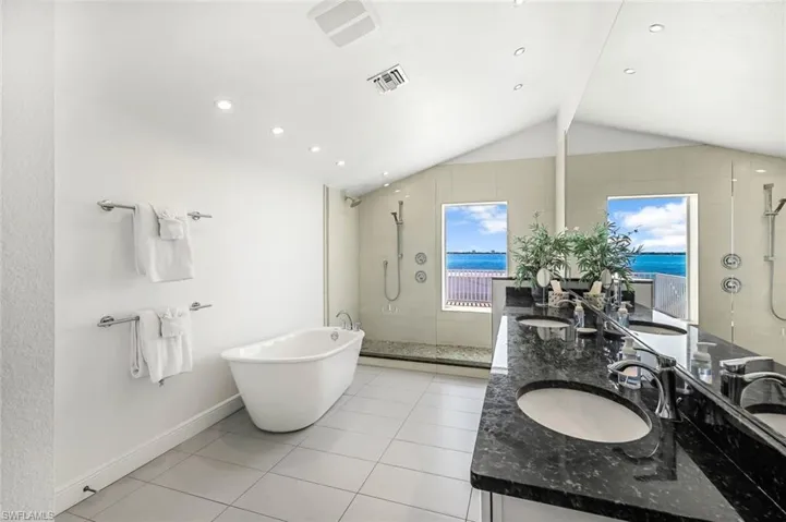 The upper story Master Suite Bathroom with separate bath tub, walk in shower, twin basins and views of the river