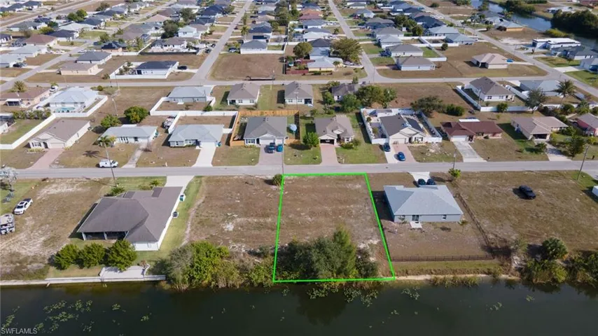 Aerial view of residential area featuring property boundaries highlighted and a large body of water