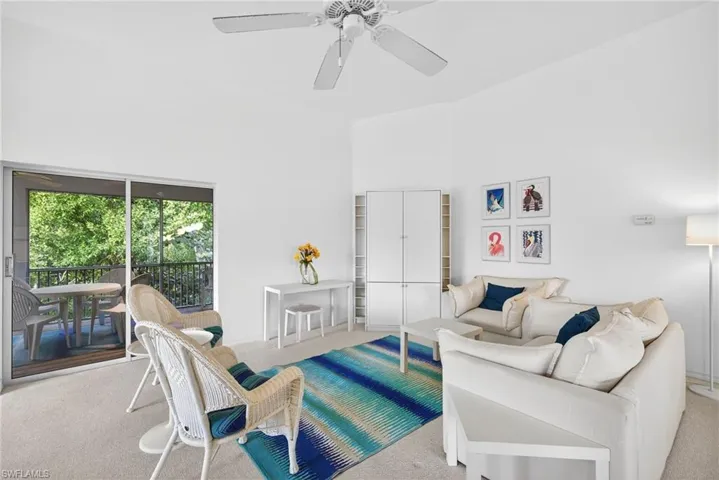 Carpeted living area with a high ceiling and ceiling fan
