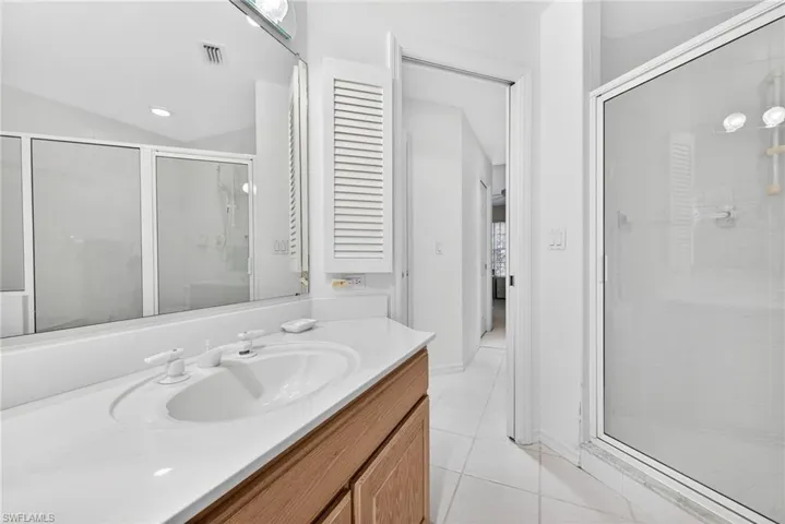 Primary Bathroom with a shower stall, vanity, light tile patterned floors, lofted ceiling, and recessed lighting