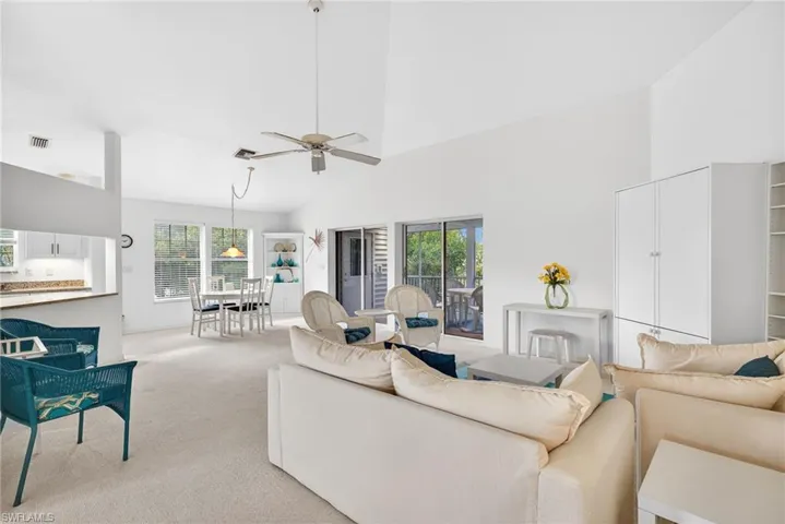 Carpeted living room featuring healthy amount of natural light, lofted ceiling, and a ceiling fan