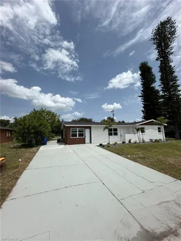 Concrete driveway leading to a single-story residence with a white and brown exterior