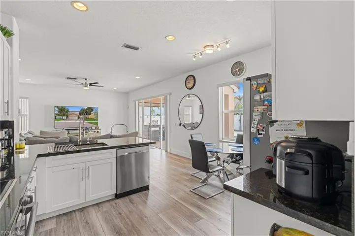 Kitchen with ceiling fan, white cabinets, light wood-type flooring, dishwasher, and a textured ceiling