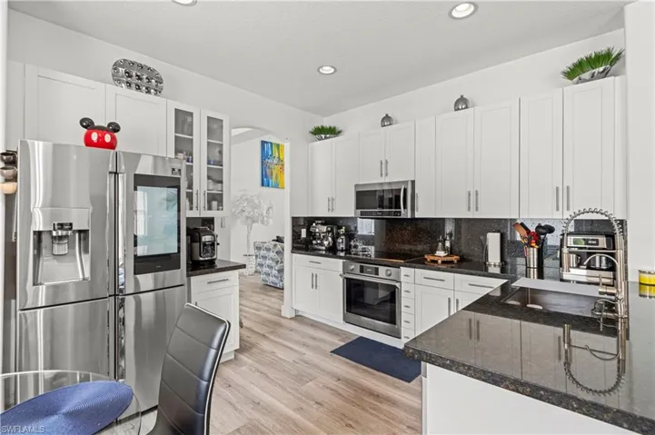 Kitchen featuring white cabinetry, light hardwood / wood-style flooring, backsplash, and stainless steel appliances