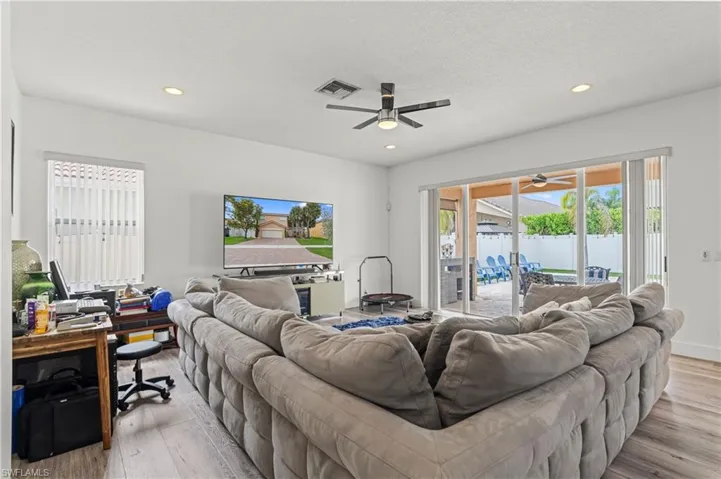 Living room with light hardwood / wood-style floors, a textured ceiling, and ceiling fan
