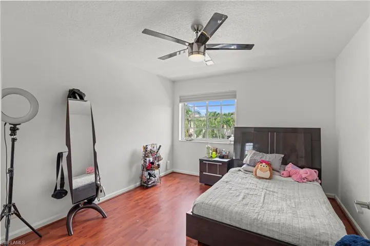 Bedroom with dark wood-type flooring, a textured ceiling, and ceiling fan