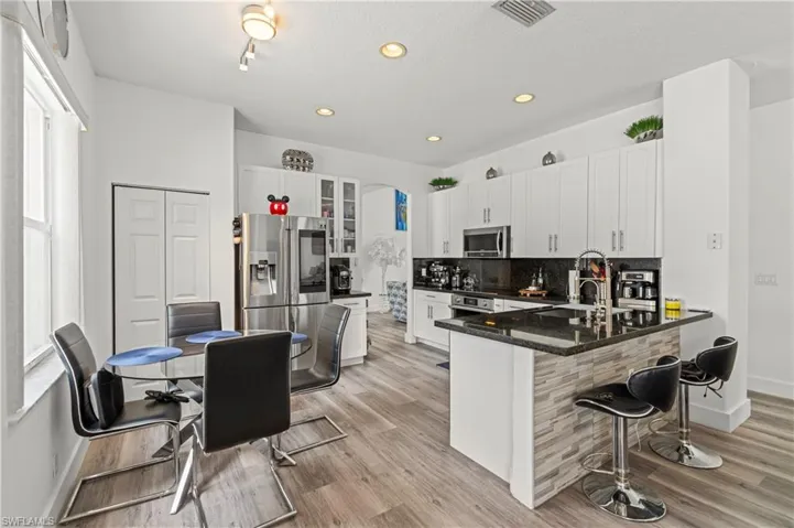 Kitchen featuring white cabinetry, light hardwood / wood-style floors, a healthy amount of sunlight, and appliances with stainless steel finishes
