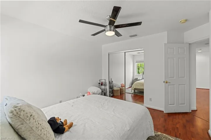 Bedroom with a closet, ceiling fan, and dark wood-type flooring