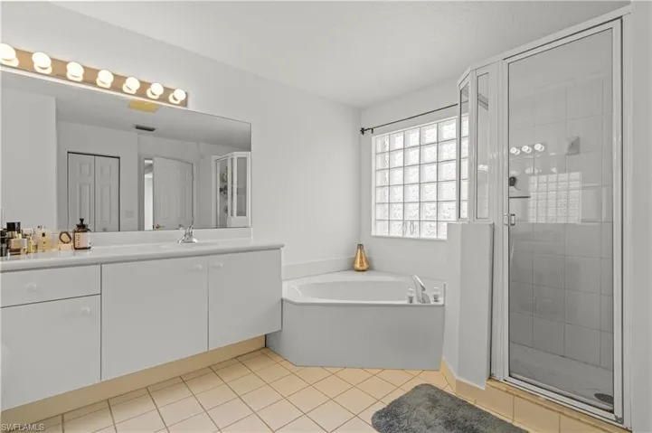 Bathroom with plus walk in shower, vanity, and tile patterned flooring