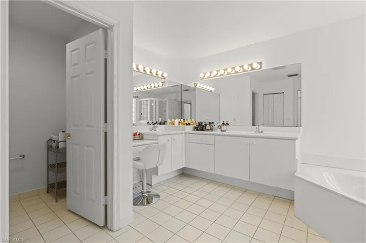 Bathroom with a tub, dual vanity, and tile patterned flooring