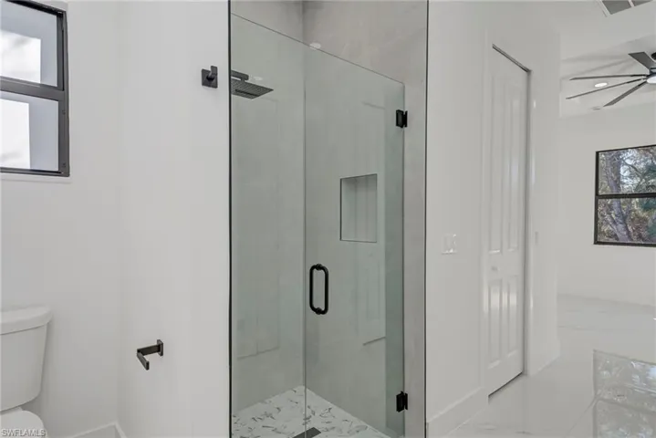 Full bath featuring a stall shower, a ceiling fan, and marble finish floors