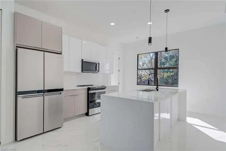Kitchen with stainless steel appliances, hanging light fixtures, light marble finish flooring, modern cabinets, and light stone counters