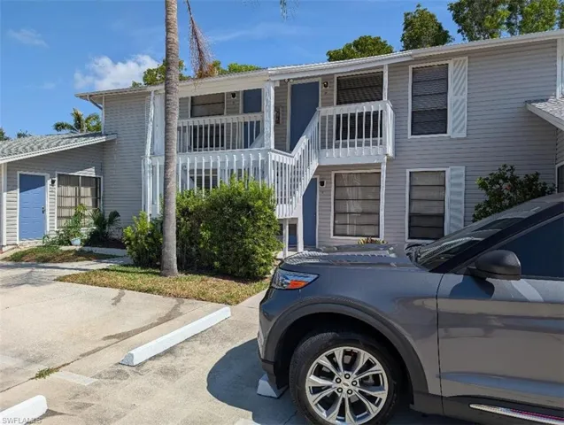 View of front of property with uncovered parking and stairs