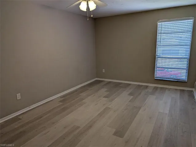 Unfurnished room featuring baseboards, light wood-style floors, and ceiling fan