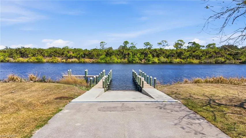 Dock area with a water view, a boat ramp, and a lawn