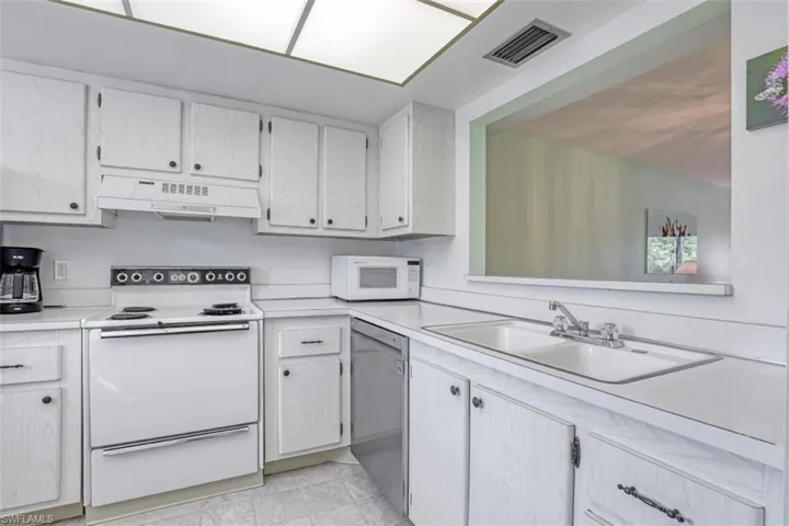 Kitchen with sink, white appliances, custom exhaust hood, and light tile patterned floors
