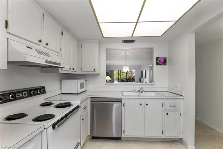 Kitchen with range, white cabinets, sink, light tile patterned flooring, and dishwasher