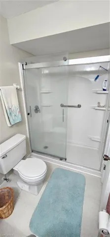 Bathroom featuring tile patterned floors, a shower with door, and toilet