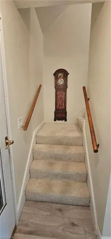Stairs with lofted ceiling, wood-type flooring, and a textured ceiling